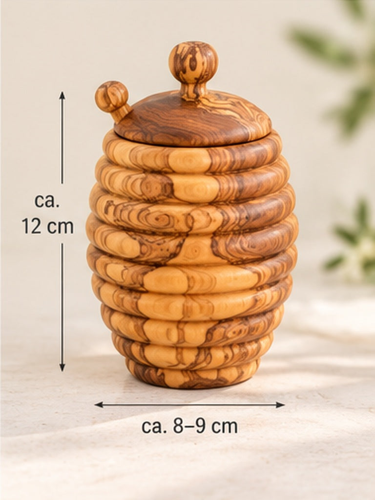 Handgefertigter Honigtopf aus Olivenholz in Bienenkorbform mit Deckel, in einer Produktansicht mit eingezeichneten Grössenangaben.