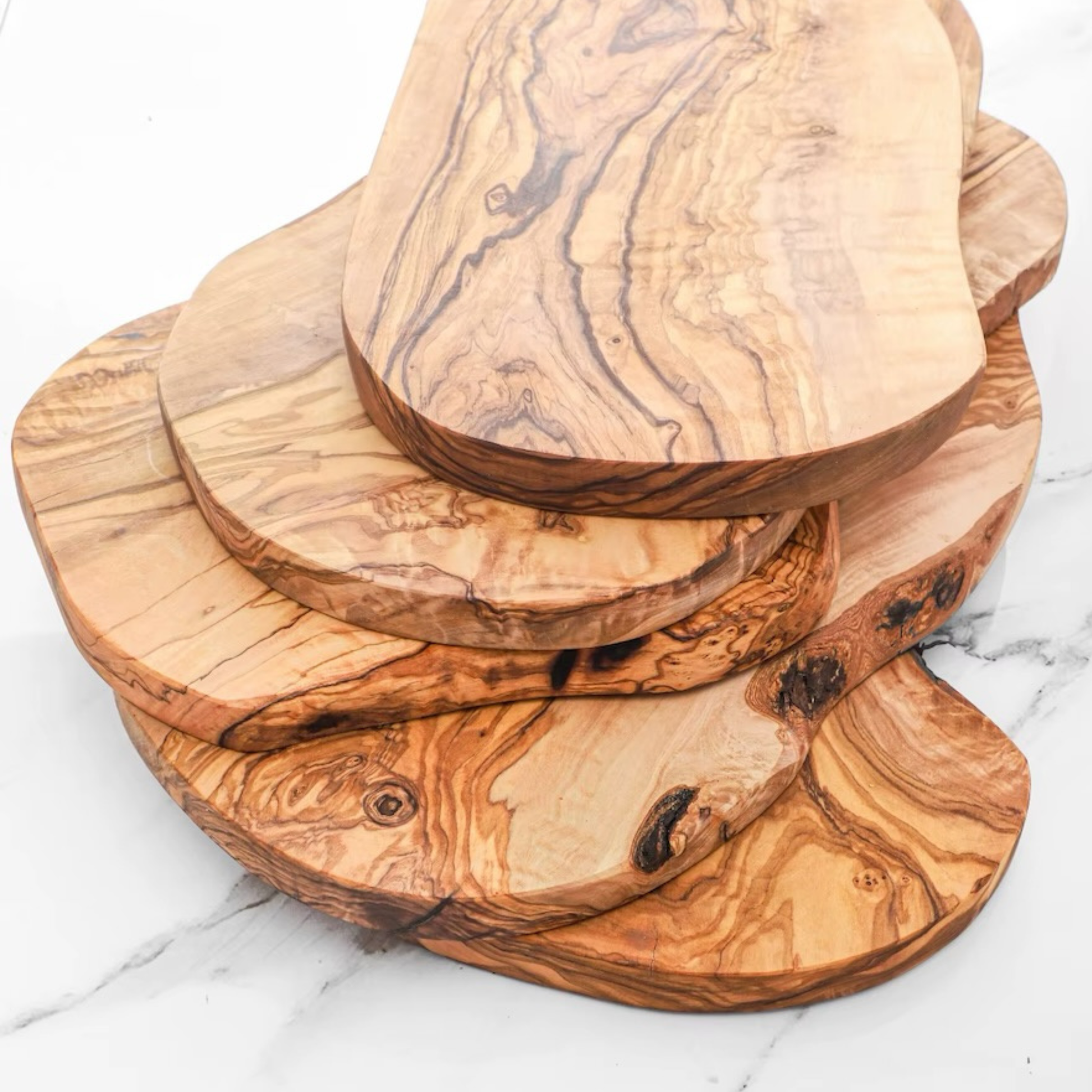 Mehrere handgefertigte Olivenholz-Bretter mit einzigartiger Holzmaserung, perfekt als Apéro-, Käse- oder Servierbrett in der Schweiz.