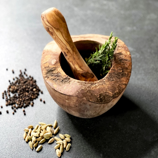 Handgefertigter Mörser mit Stößel aus mediterranem Olivenholz auf heller Küchenarbeitsplatte