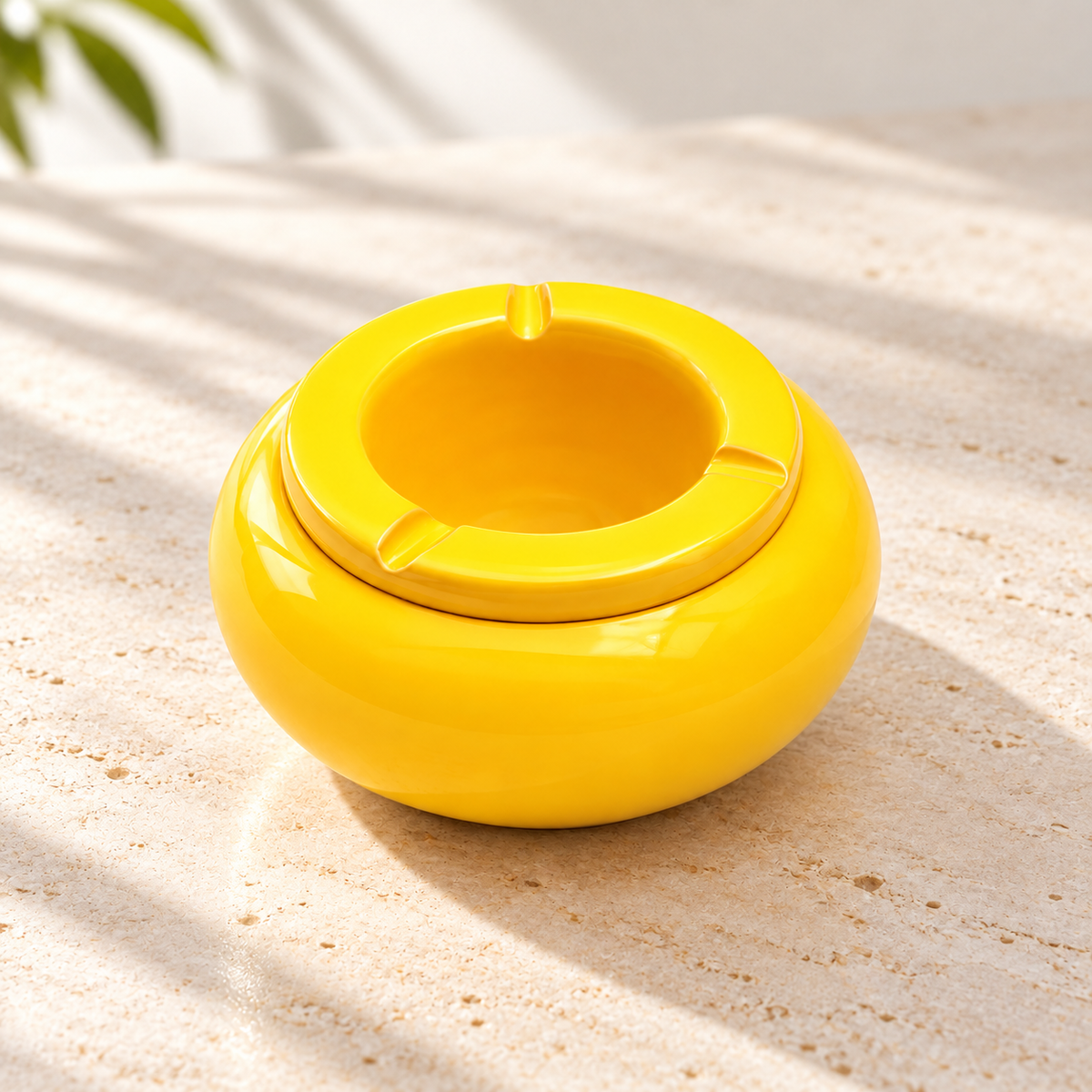 Gelber Design-Aschenbecher aus glänzender Keramik als farbenfroher Blickfang auf einem hellen Tisch im modernen Wohnambiente