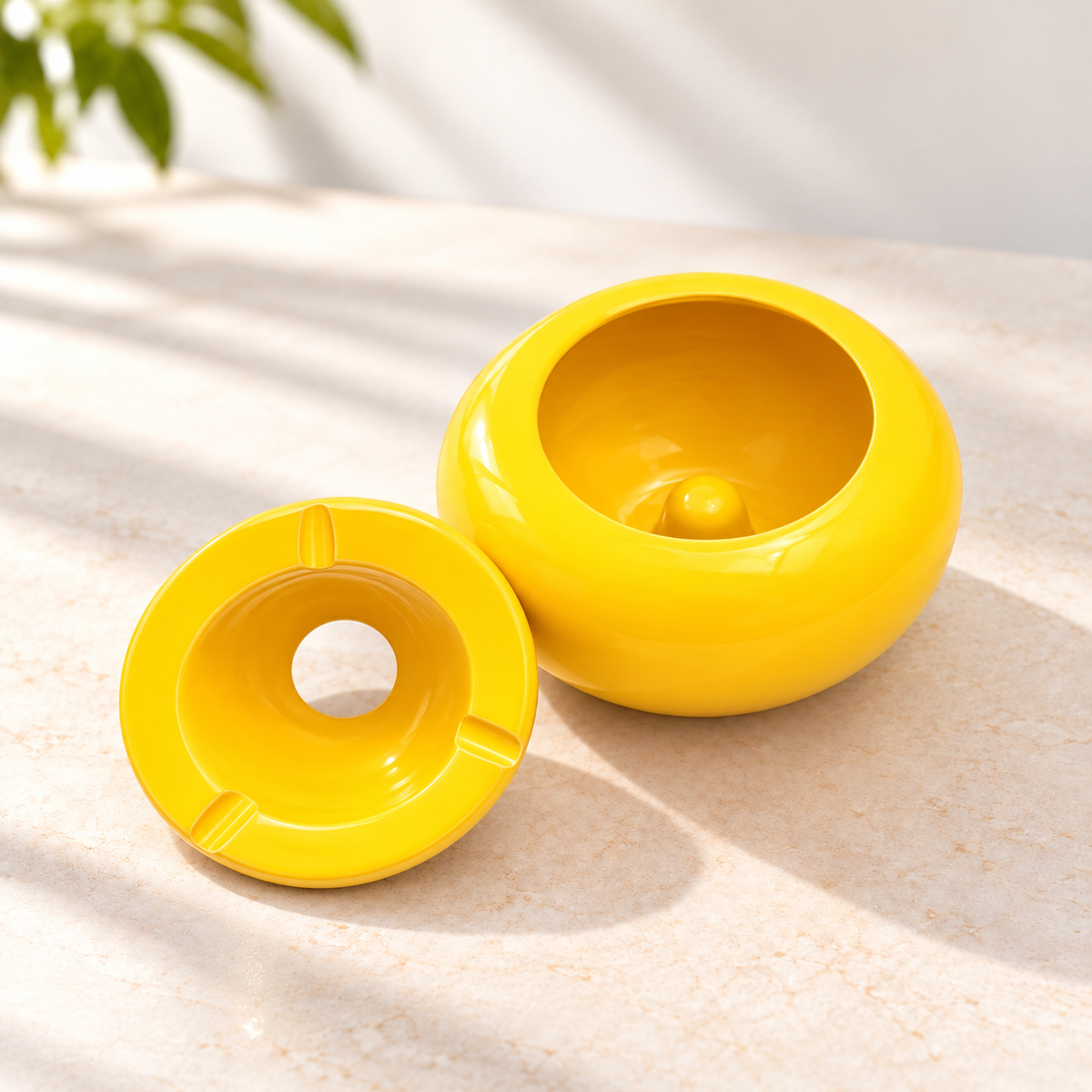 Runder Design-Aschenbecher aus gelber Keramik in der Draufsicht mit drei Zigarettenablagen und glänzender Oberfläche.