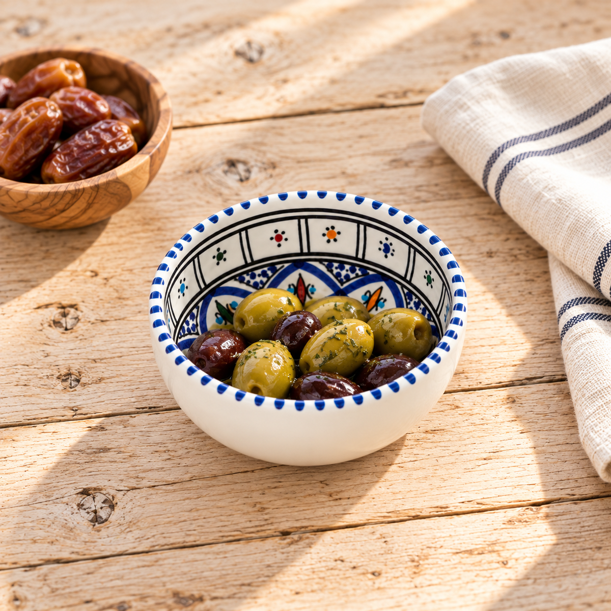 Handbemalte Keramikschale aus Tunesien, 13 cm, mit grünen und schwarzen Oliven auf hellem Holztisch – mediterrane Olivenschale