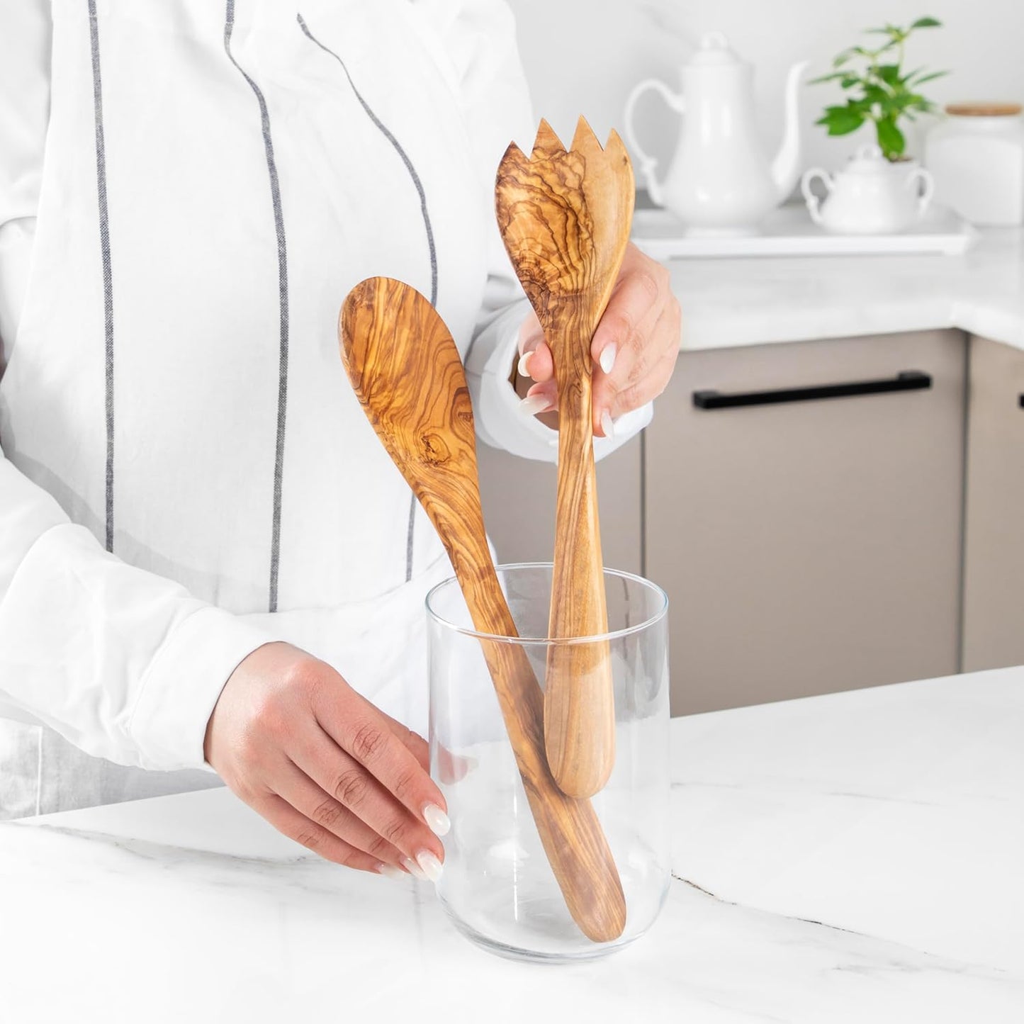 Salatbesteck aus Olivenholz in Aktion beim Mischen und Servieren eines grünen Salats – nachhaltiges Naturprodukt von MediterraneanArt