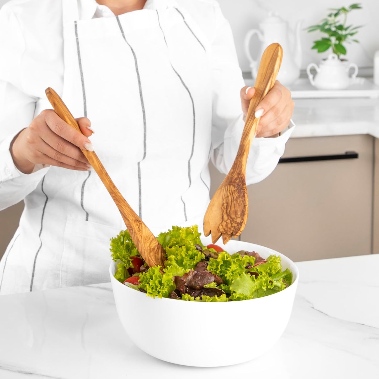 Handgefertigtes Salatbesteck aus Olivenholz beim Servieren eines frischen Salats – mediterrane Qualität veredelt in der Schweiz