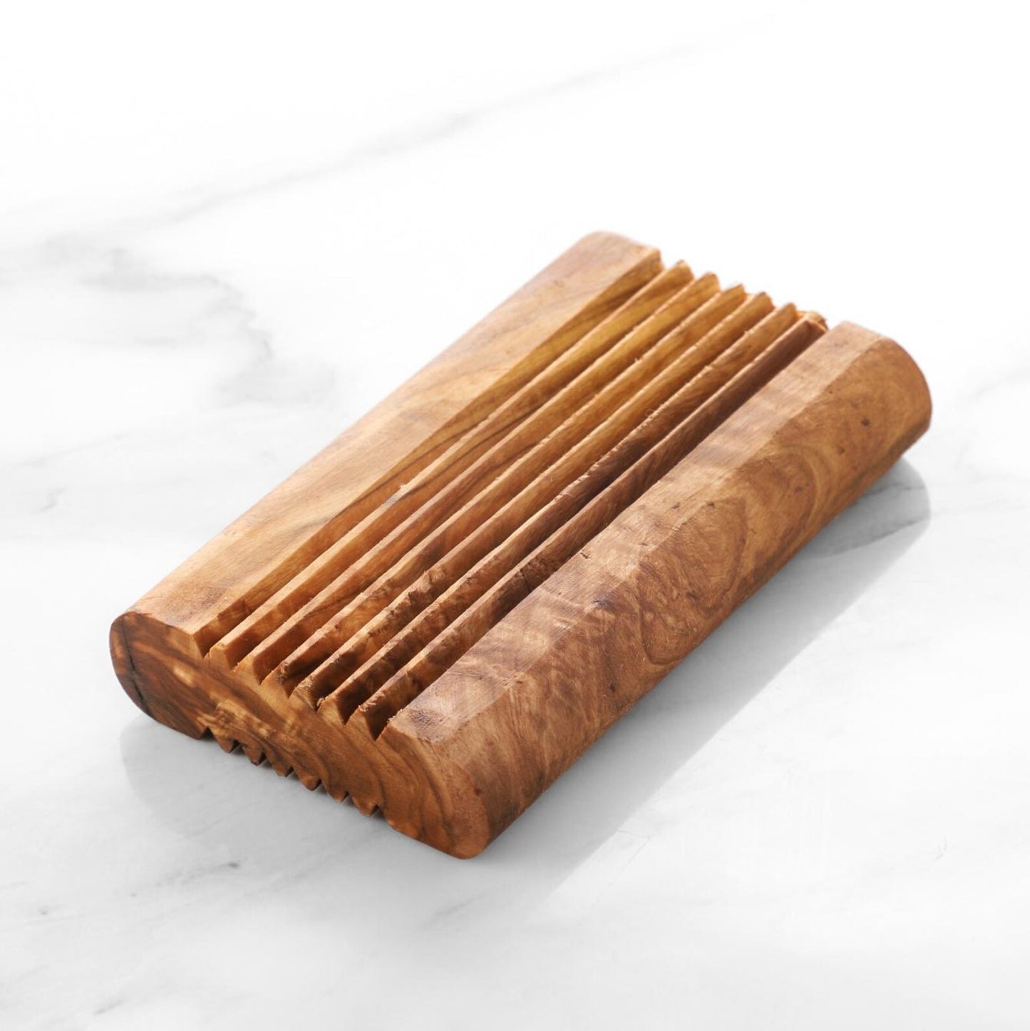 Natürliche Seifenablage aus Olivenholz auf weißem Waschtisch, minimalistisch dekoriert.